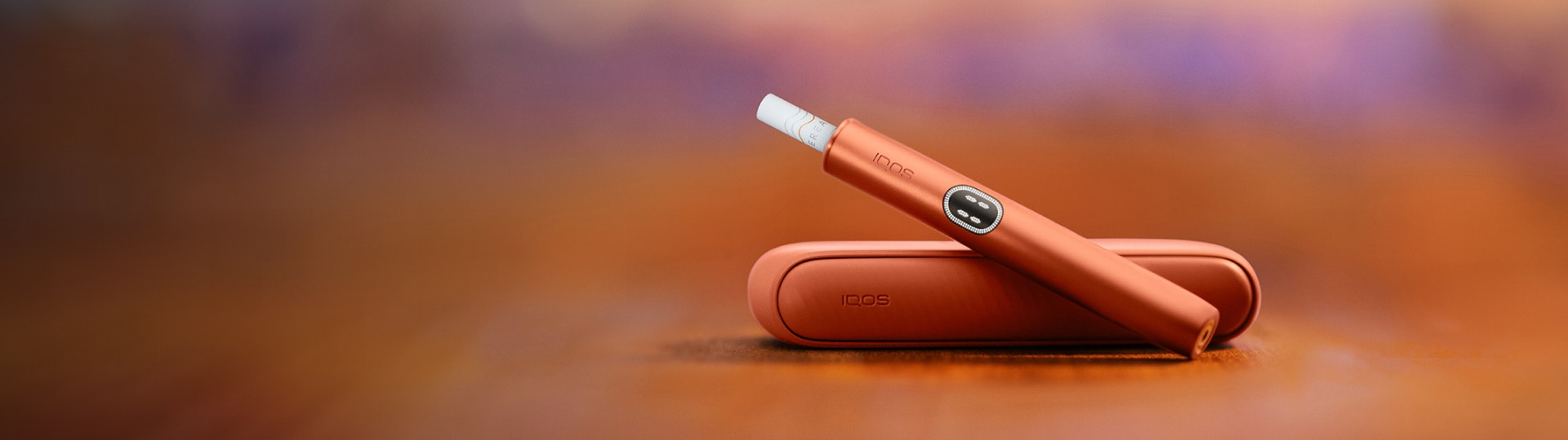 An IQOS device held by one person and a smartphone held by another person.